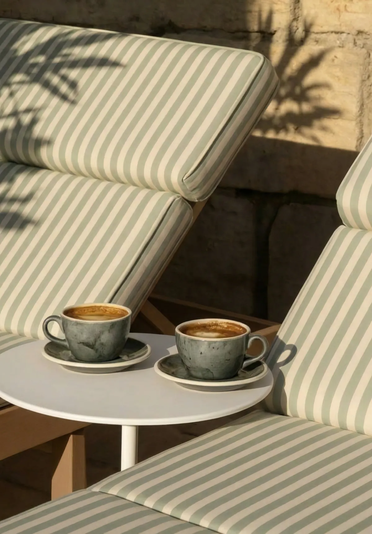 Dos cafés sobre una mesita junto a tumbonas de rayas