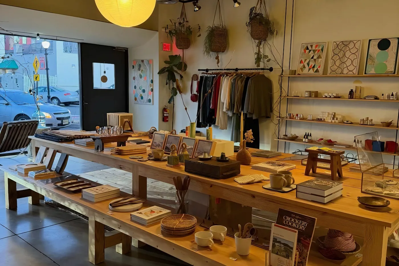 Interior de una concept store con ropa y objetos sobre mesas de madera