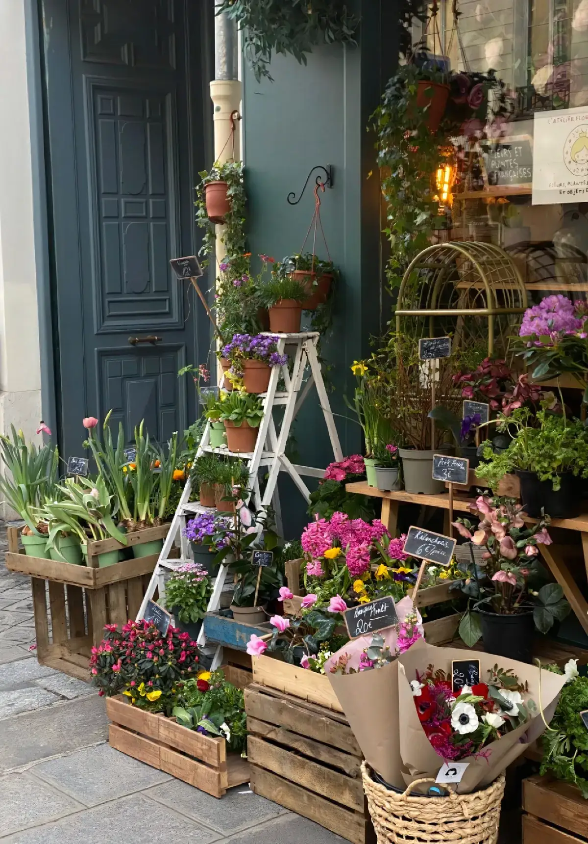 Flores de una tienda de barrio expuestas sobre una escalera de madera en la acera