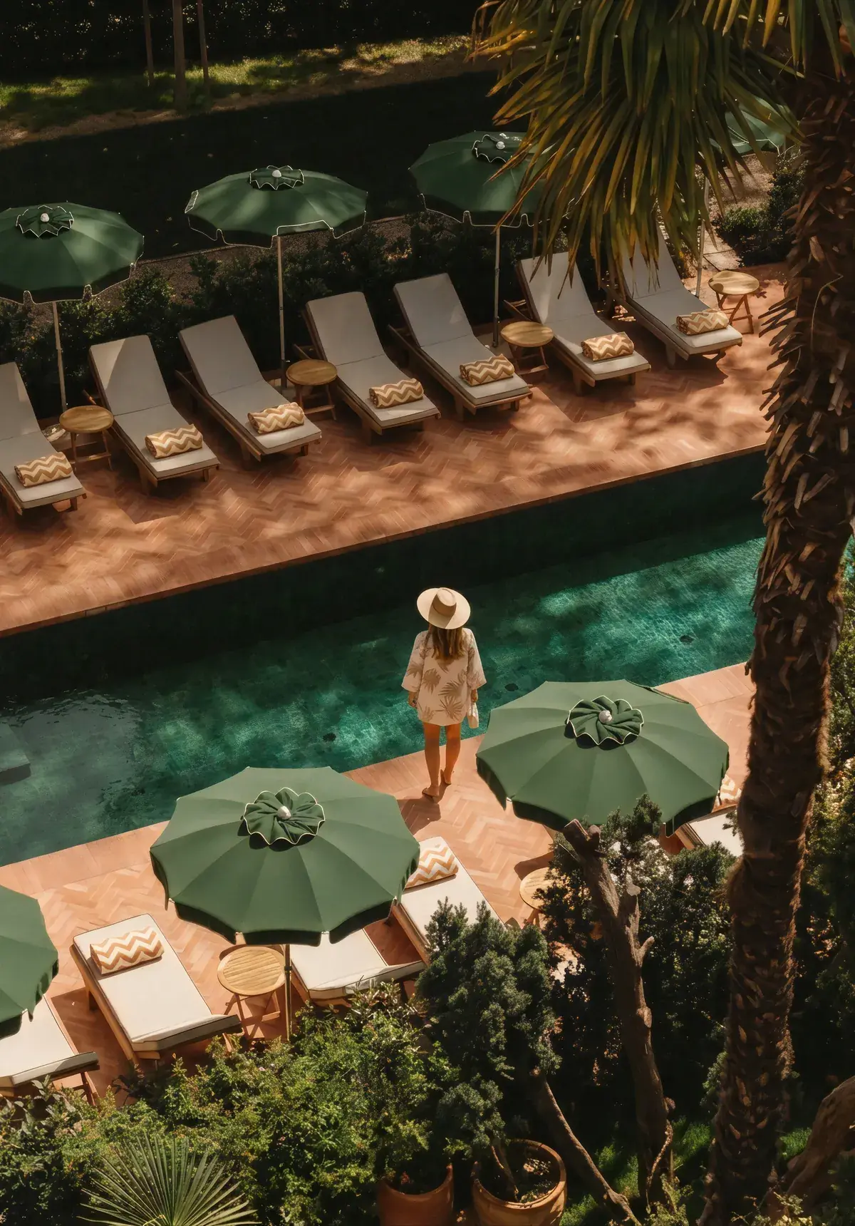 Hamacas y sombrillas verdes junto a la piscina de un hotel