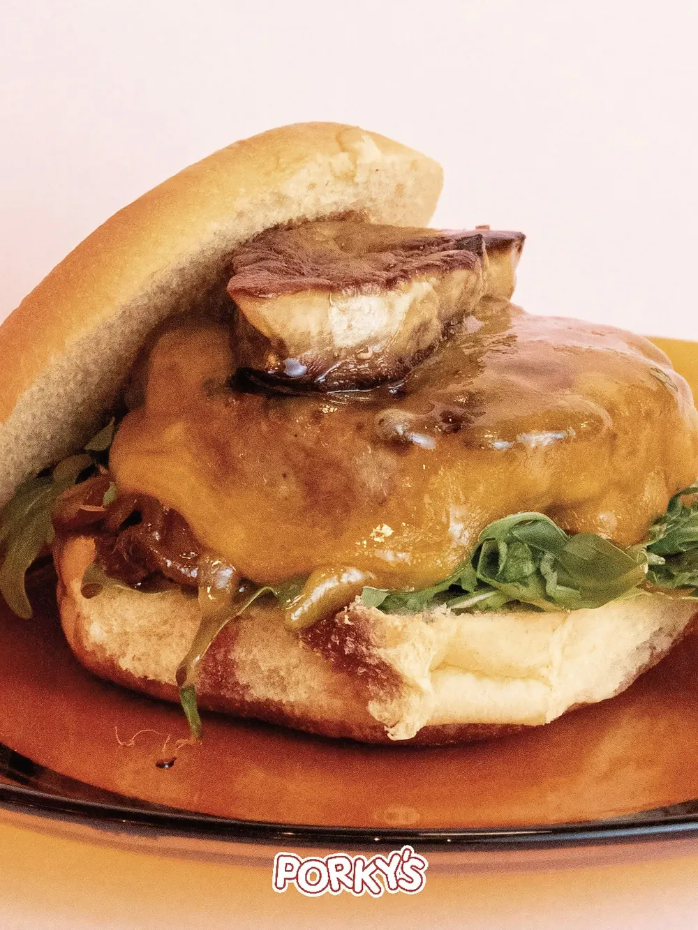 Sándwich de Porky’s con queso fundido servido en plato naranja